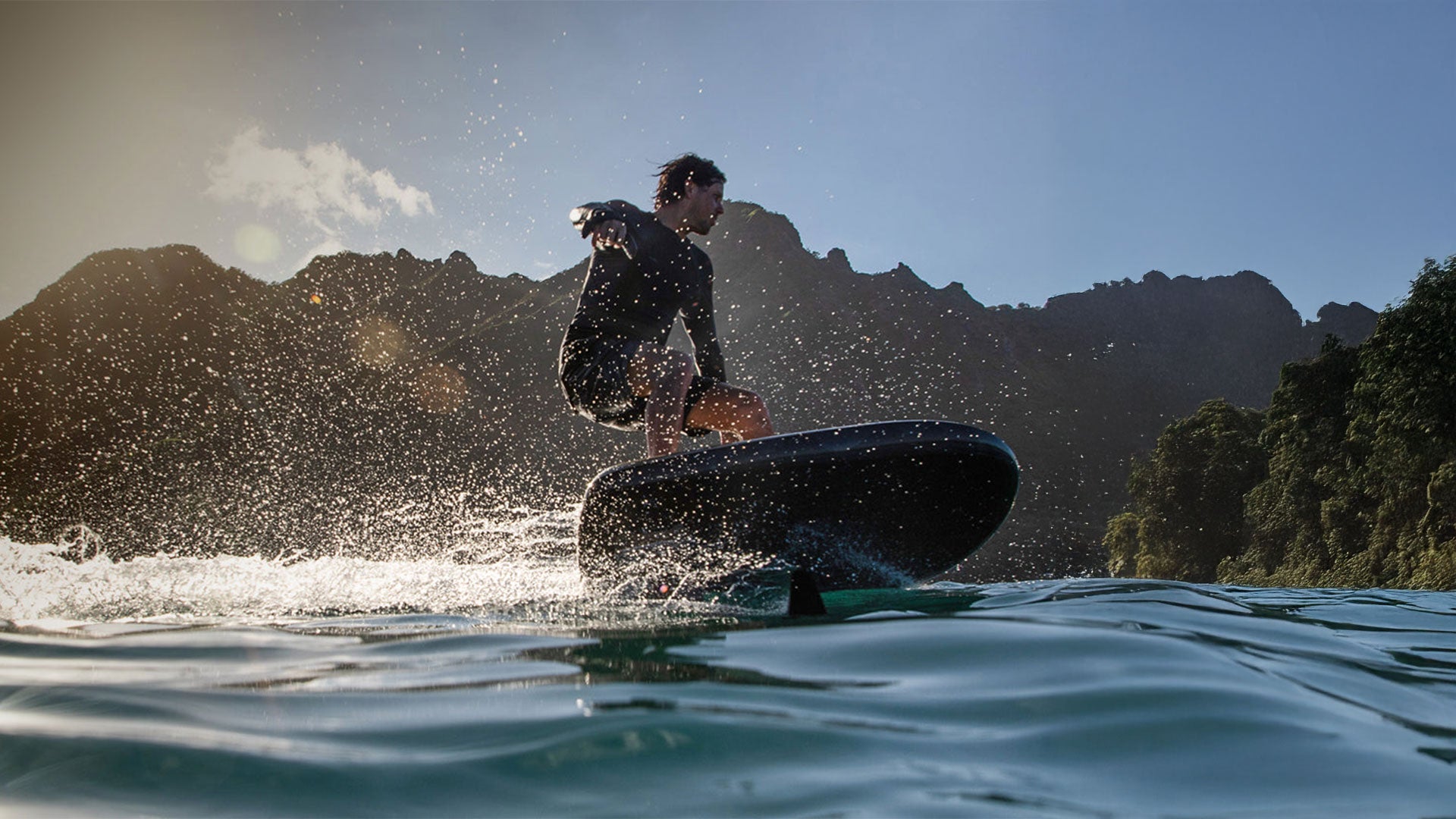 A man sprays water into the air with his Fliteboard while foiling a steep curve.