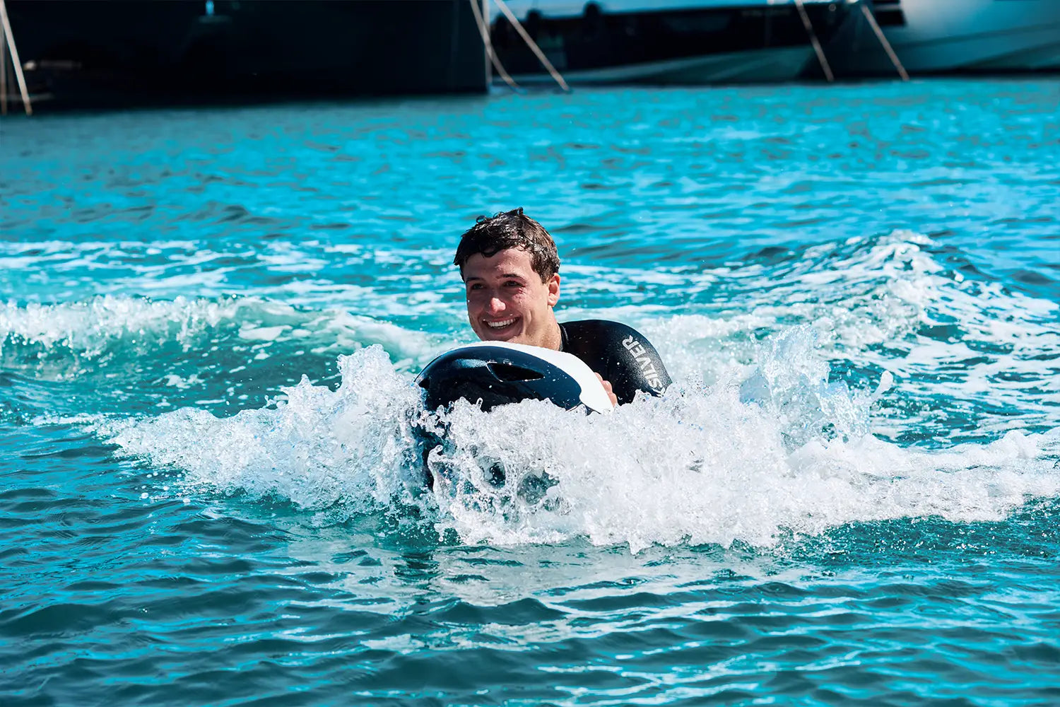 A man smiles at the camera as he rides a white Seabob on the sea in Mallorca.