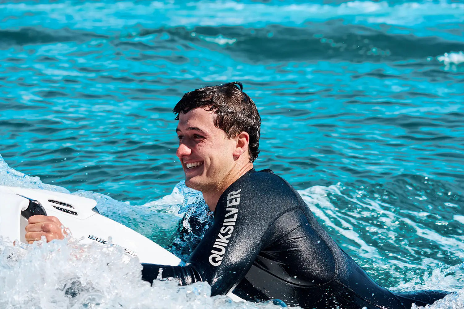Ein Mann lächelt, während er mit einem weißen Seabob auf dem Meer in Mallorca fährt.