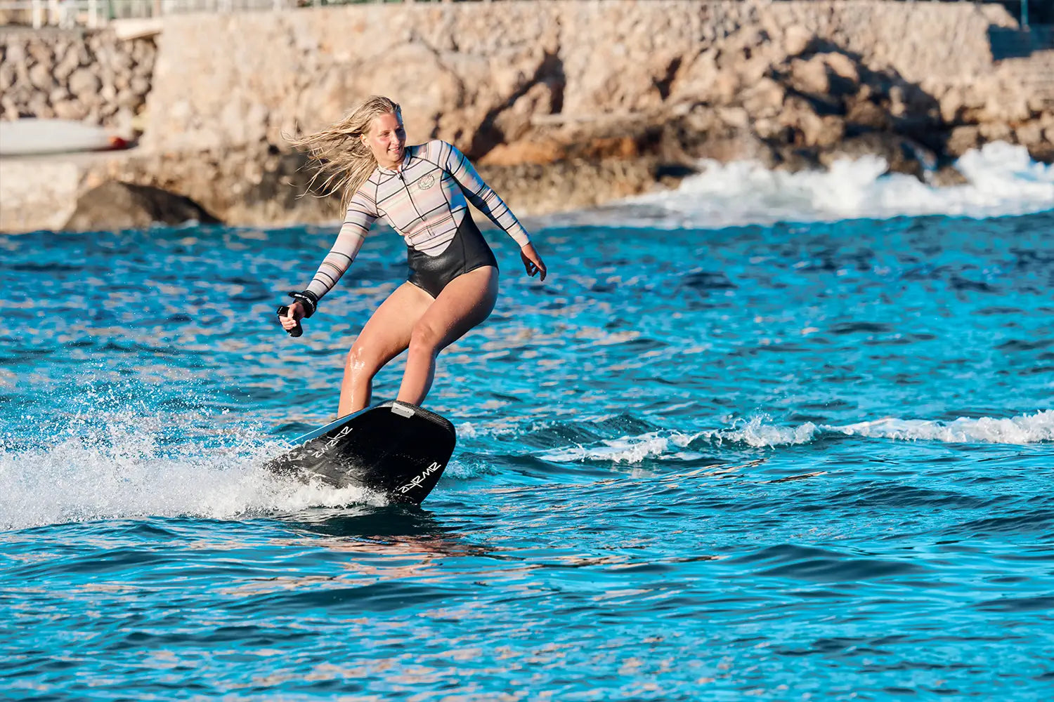 A woman rides an awake jetboard on the sea in Mallorca and has a lot of fun.