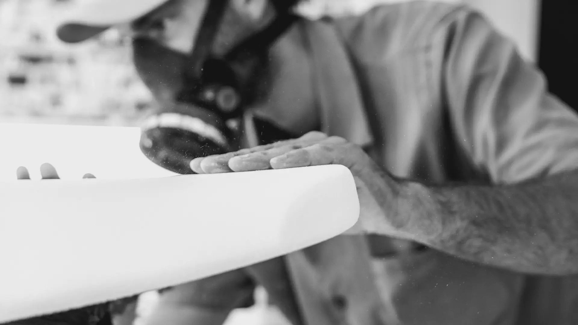 A black and white picture of a man with a protective mask holding a Lind surfboard.