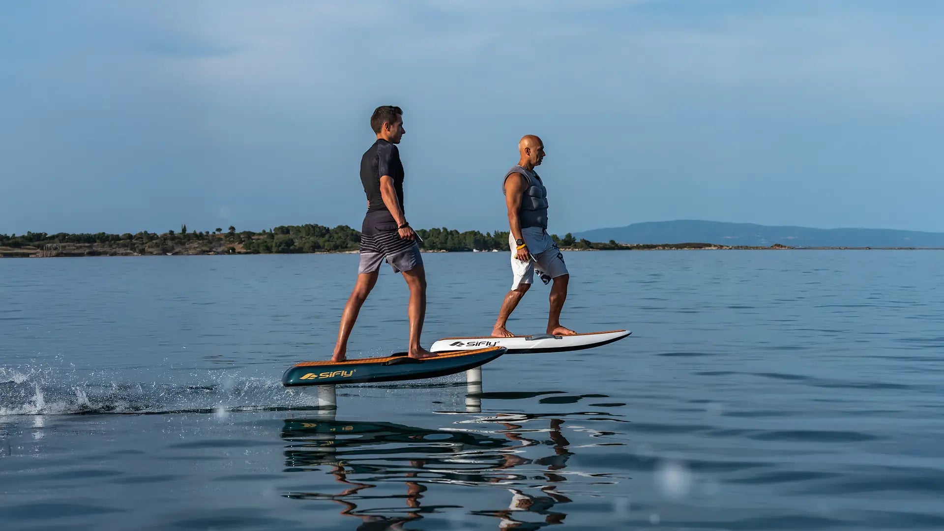 Two people foiling on a sifly board on the sea.