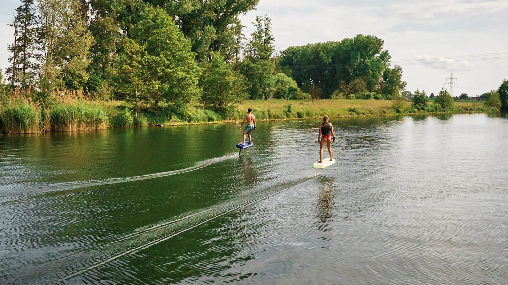 Two people standing next to their fliteboards in a river in Germany.