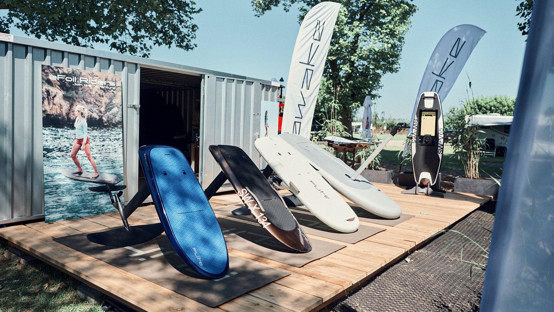Flitebaords and Awake Jetboards are lined up on a wooden walkway at the eFoil Riders station in Würzburg.