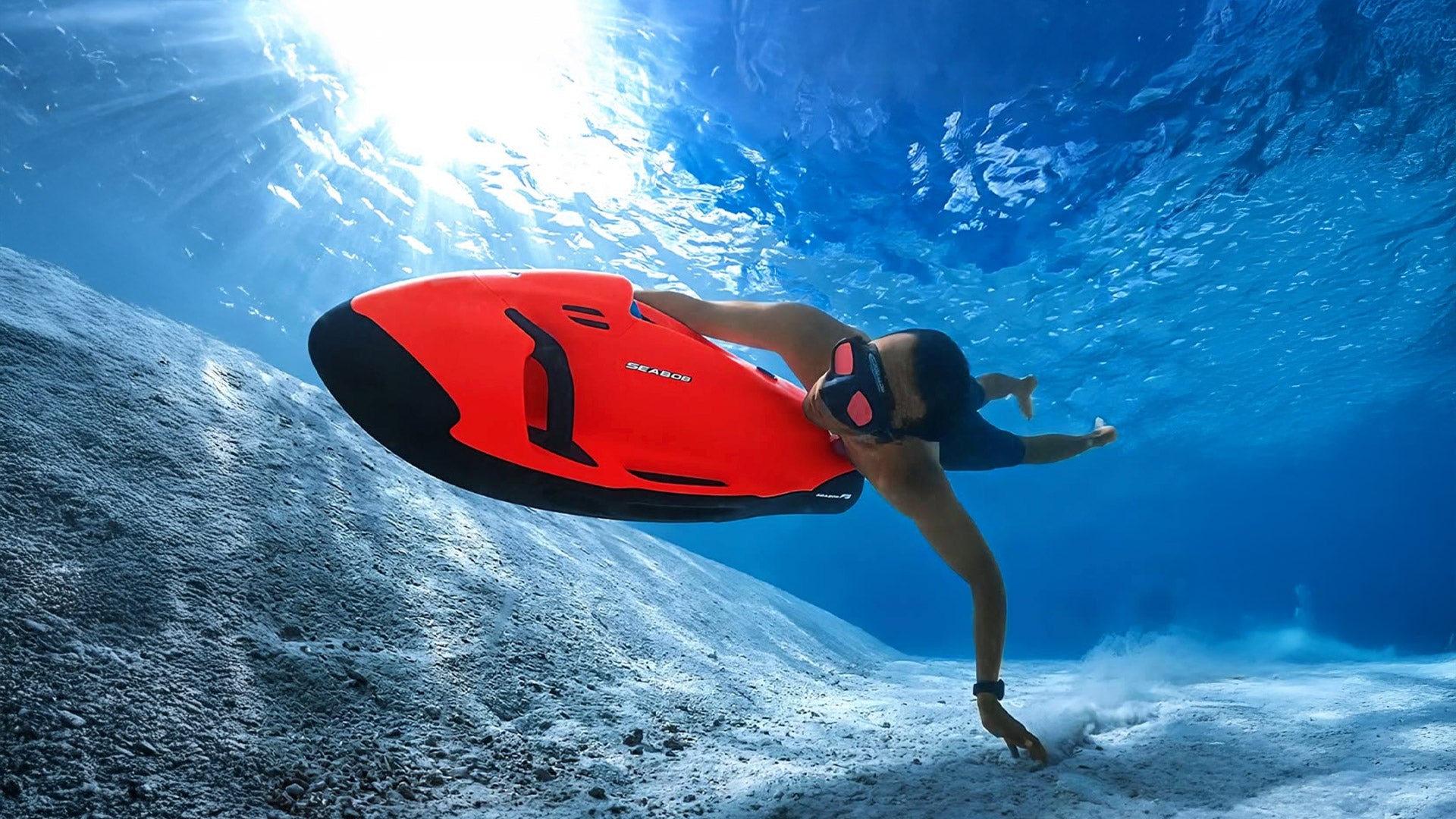 A man is diving with a red Seabob.