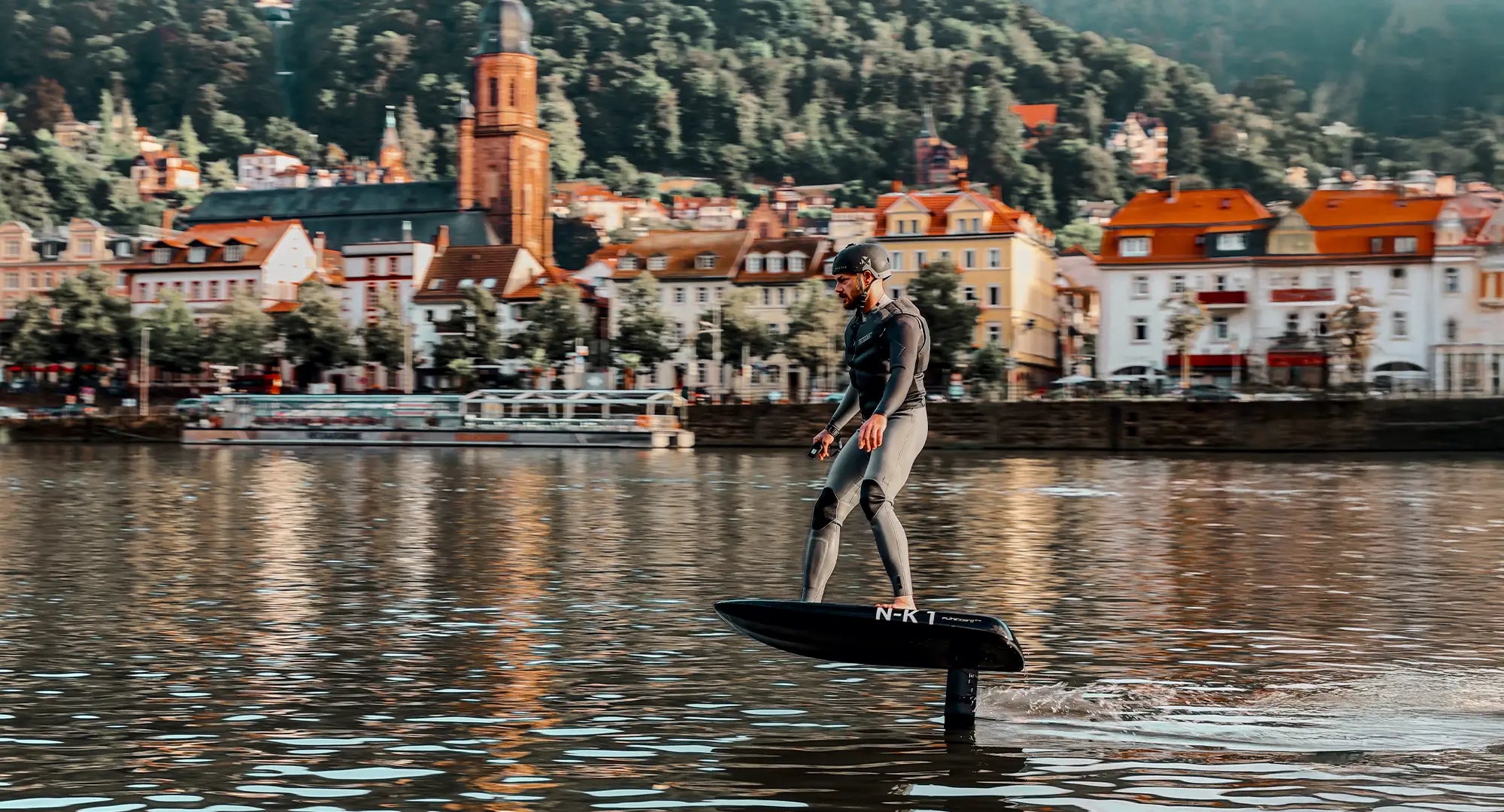 A man efoils on his Fliteboard on the Neckar in Heidelberg.