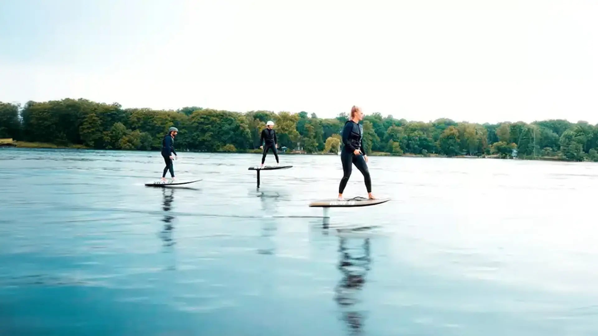 Three people ride their Fliteboards on the water.
