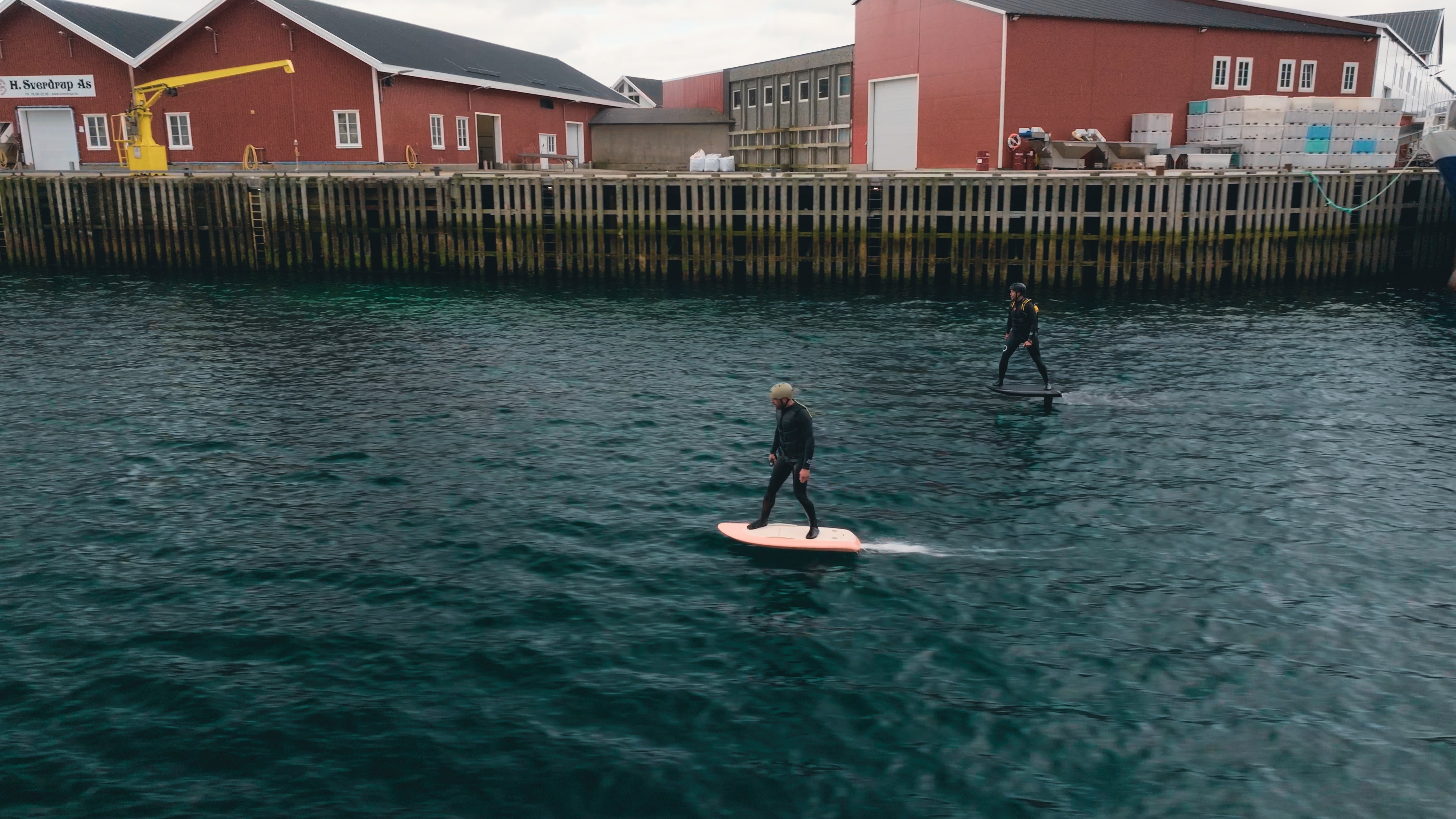Two people in wetsuits foiling on a fliteboard in Norway.
