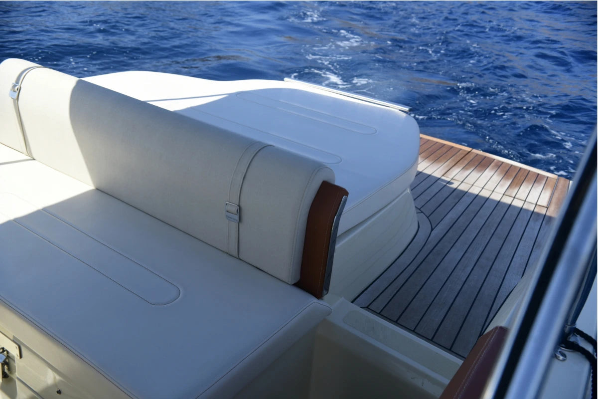 Boat seat with a white cushion on a boat deck with blue water in the background