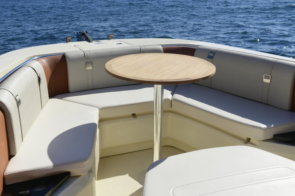 Interior of an invictus boat with a round table and seating area on a body of water.