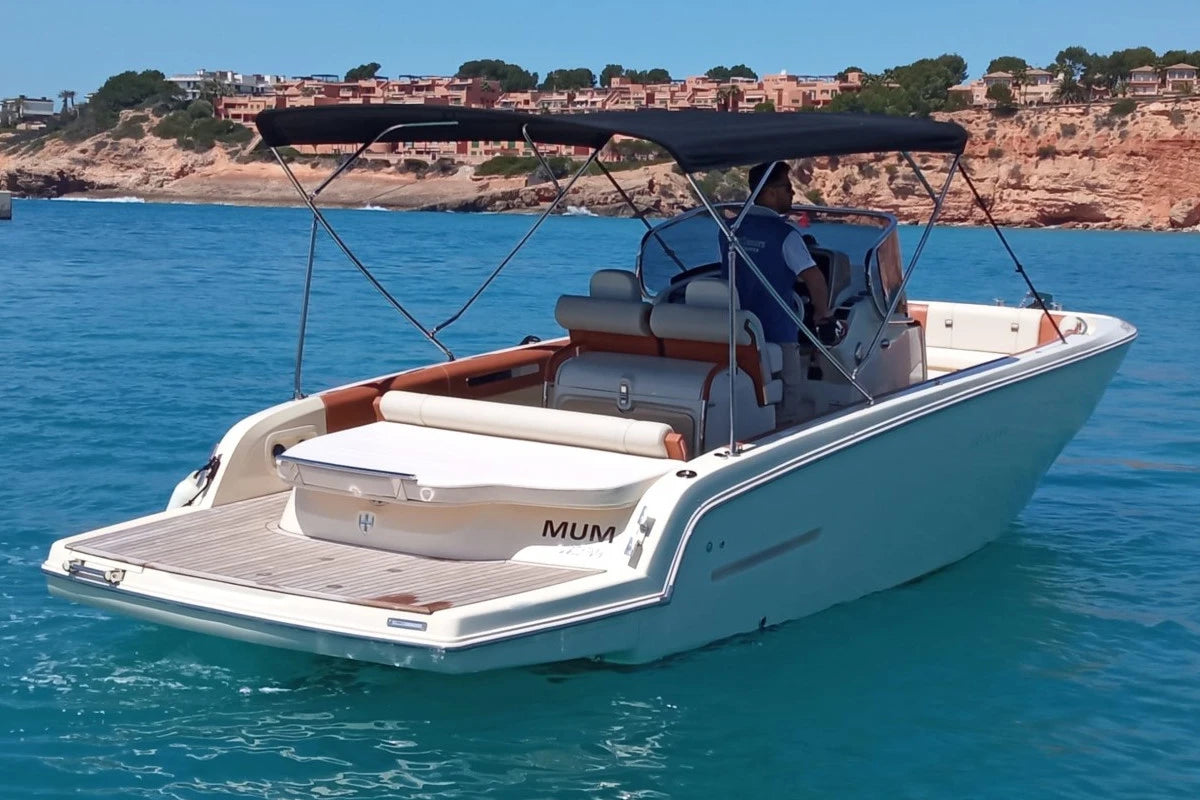 White boat with a canopy on a body of water with cliffs in the background