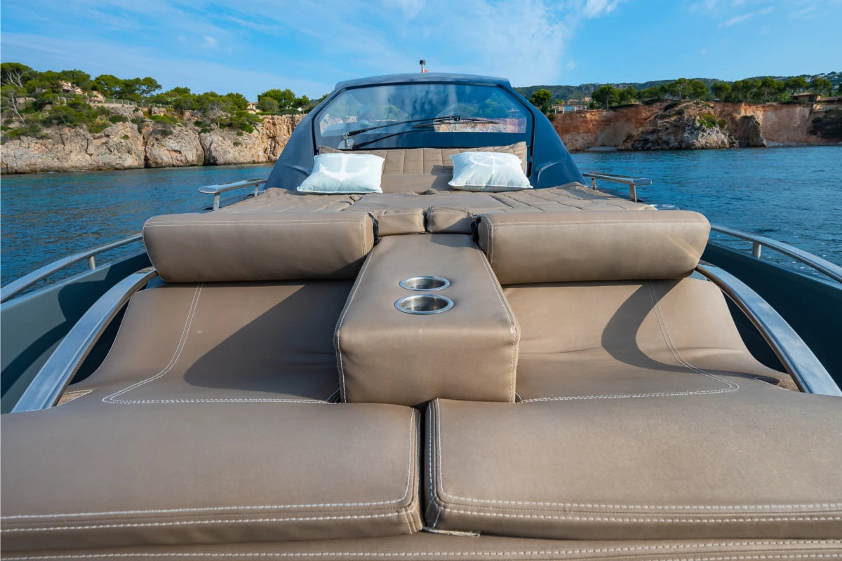 Sinner boat interior with brown leather seats and cup holders on a body of water with cliffs in the background.