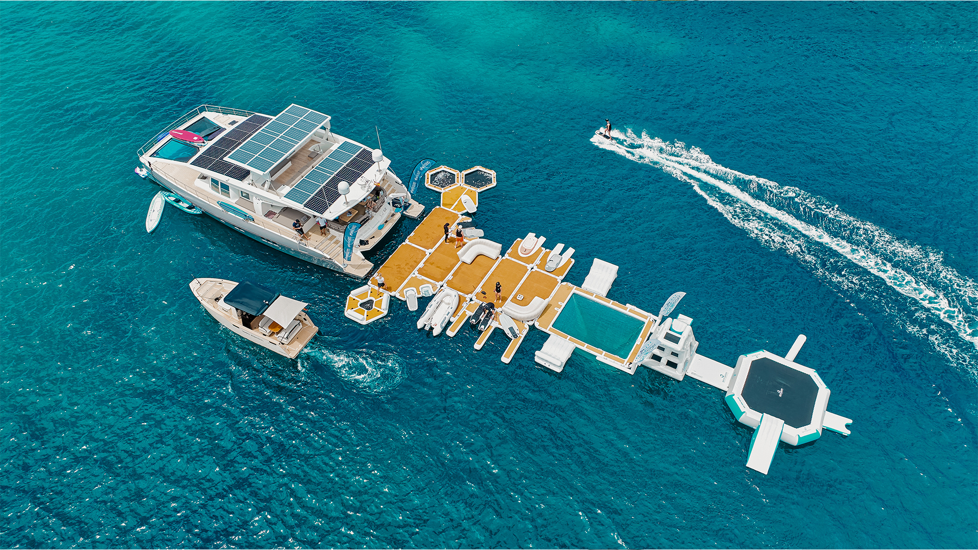 From above you can see a yacht on the sea with various Yachtbeach platforms hanging from it.