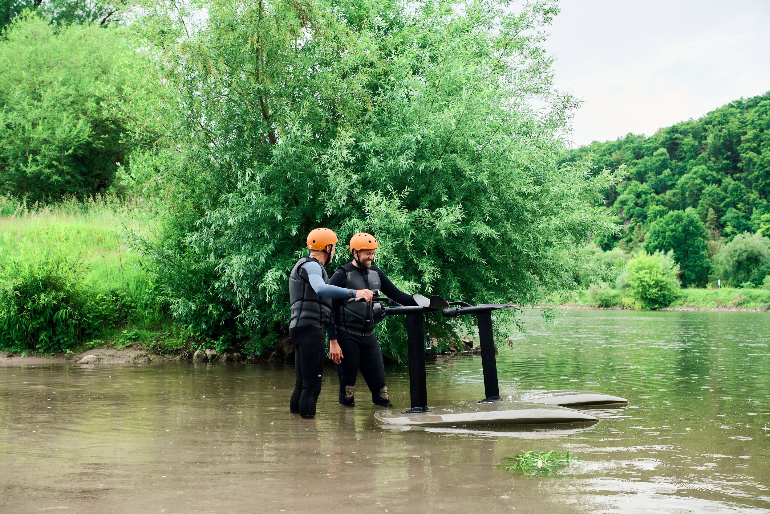 Two people standing next to their fliteboards in a river in Germany.