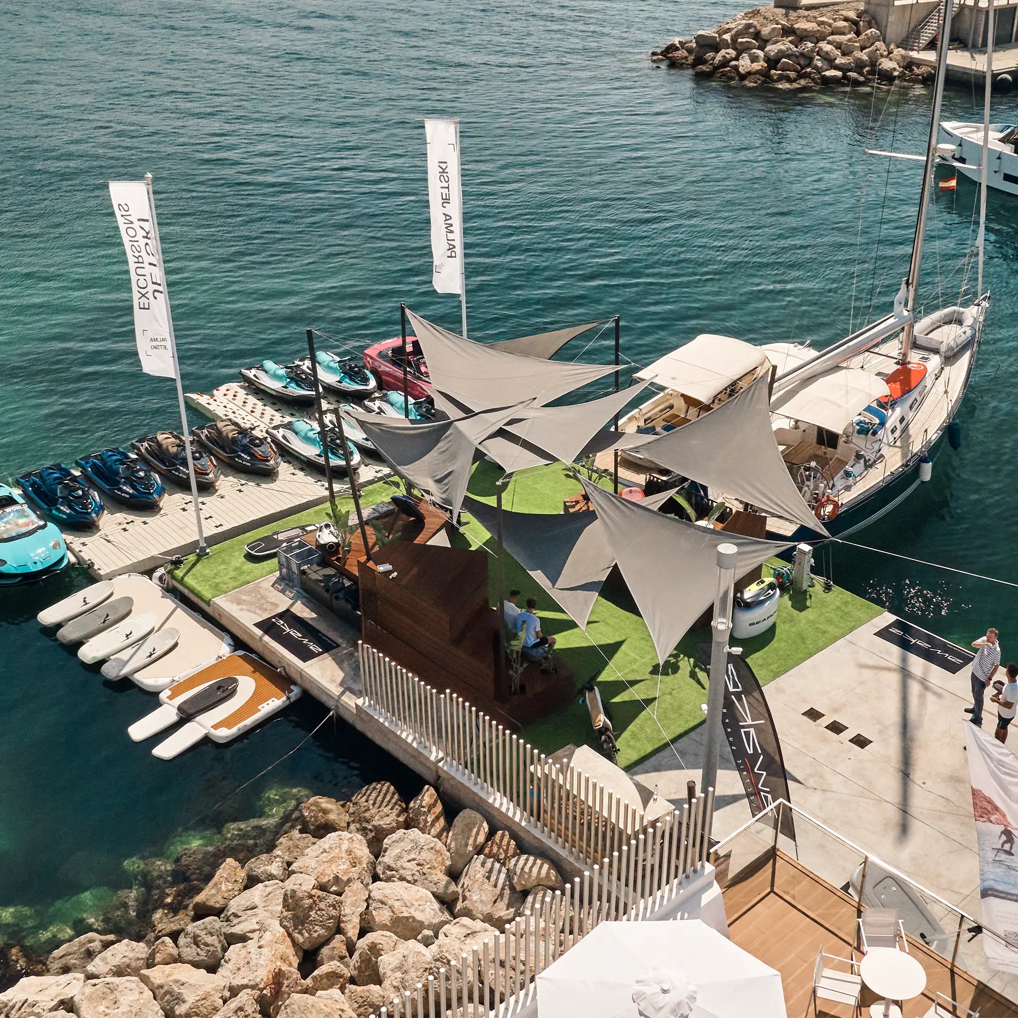 The picture shows the eFoil-Riders Location on Port Calanova in Mallorca from above. You can see the launch, fliteboards, awake boards and some other water gadgets. 